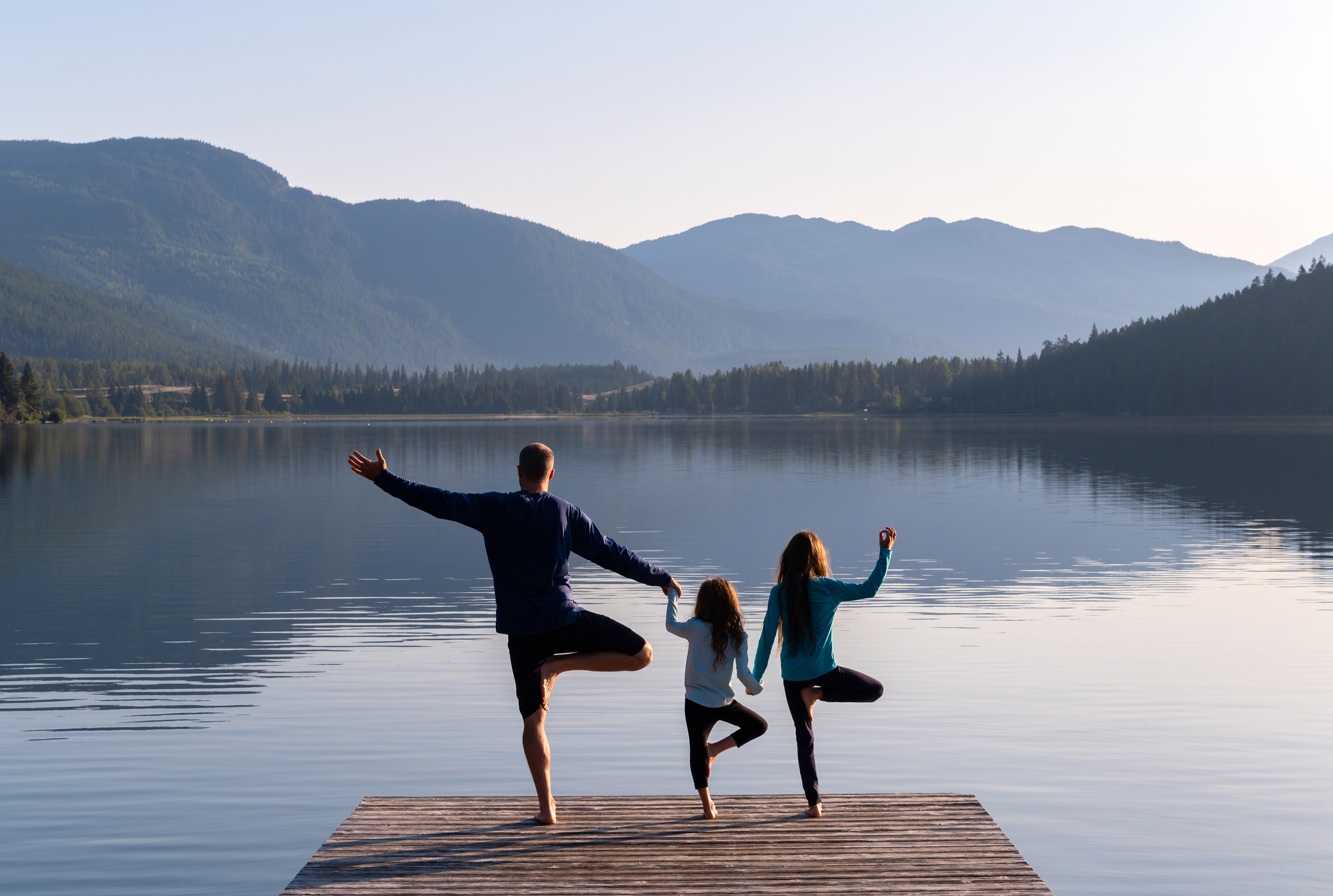 family doing yoga pose on a dock